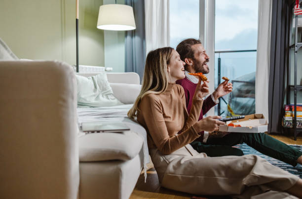 couple eating pizza and watching tv - junk food stock pictures, royalty-free photos & images
