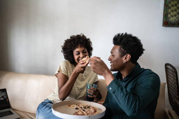 couple eating pizza together at home - junk food stock pictures, royalty-free photos & images