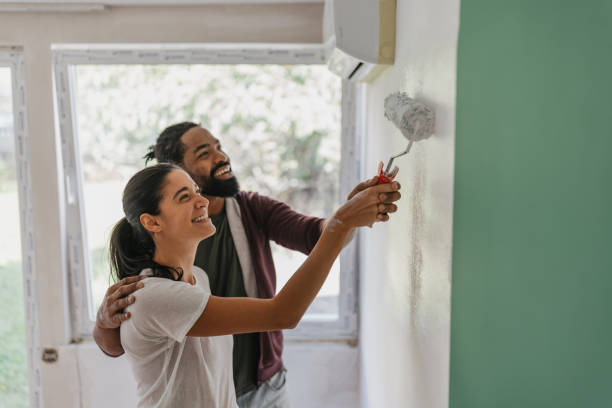 couple having fun painting a wall together - home decoration stock pictures, royalty-free photos & images