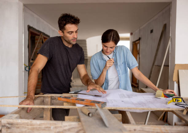 couple looking at the blueprint of their new house at the construction site - home decoration stockfoto's en -beelden