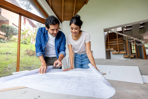 couple looking at the blueprints while renovating their house - home decoration stock pictures, royalty-free photos & images