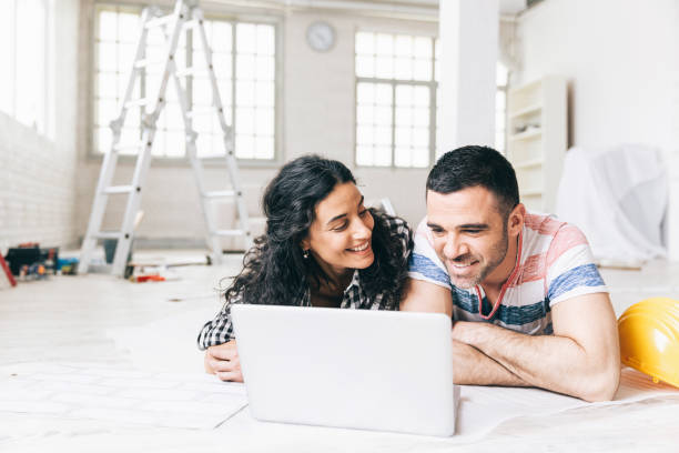 couple lying on the floor in a new apartment and using a laptop - home decoration stock pictures, royalty-free photos & images