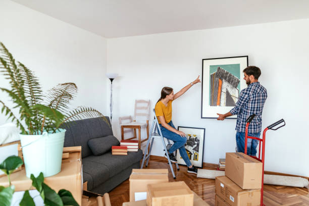 couple moving in new apartment, woman and man putting picture on the wall - home decoration stock pictures, royalty-free photos & images