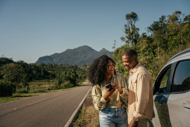 couple next to car using smartphone - travel stock pictures, royalty-free photos & images