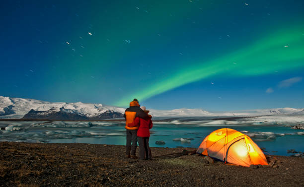 couple outside of their tent looking at northern lights in the sky - travel photos et images de collection