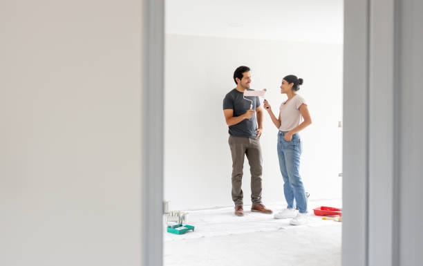 couple painting a wall together while renovating their house - home decoration stock pictures, royalty-free photos & images