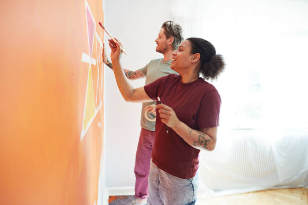 couple painting design on orange wall at home - home decoration stock pictures, royalty-free photos & images
