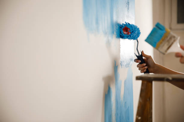 couple repainting the white wall into blue color - home decoration stock pictures, royalty-free photos & images