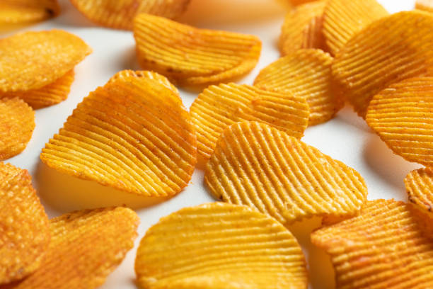 crispy fried potato chips are scattered on a white background or table. corn spicy fatty chips with paprika and spices. the concept of unhealthy diet and lifestyle, accumulation of excess weight. copy space. background of foo
