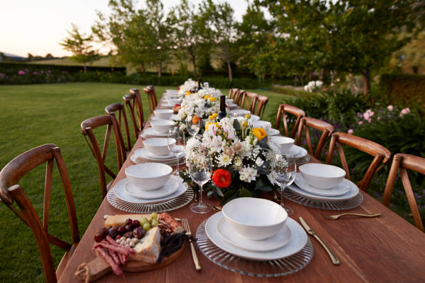 crockery arranged on long table for wedding dinner - garden decoration stockfoto's en -beelden
