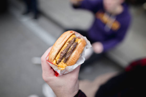 cropped hand of person holding burger,san francisco,california,united states,usa - junk food stock pictures, royalty-free photos & images