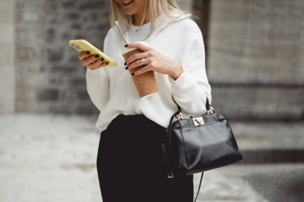 cropped image of businesswoman. midsection of a fashionable woman using smart phone and having a coffee break outdoors. - junk food stock pictures, royalty-free photos & images