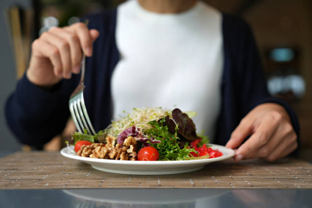 cropped image of woman having healthy green salad with alfalfa sprouts, cherry tomatoes, walnuts, leafy vegetables, olives, and salad dressing. - food stock pictures, royalty-free photos & images