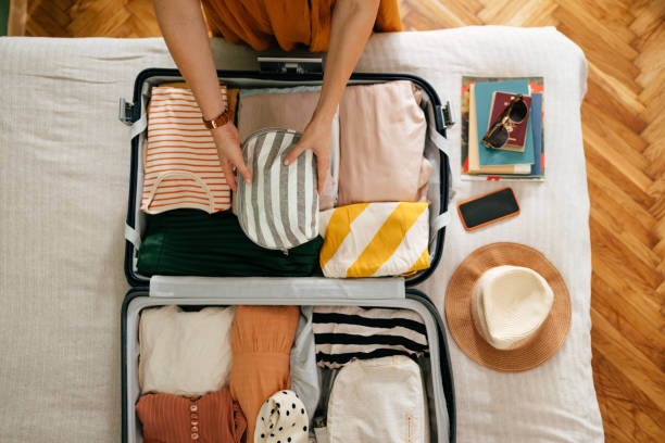 cropped photo of an unrecognizable woman putting a cosmetic bag in her suitcase - travel stock pictures, royalty-free photos & images