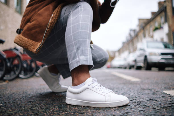 crouching man tying shoelaces on urban road - fashion stock pictures, royalty-free photos & images