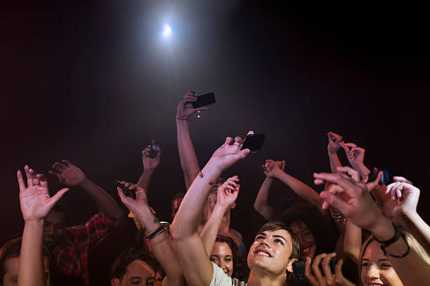 crowd in nightclub holding up cell phones - concert stock pictures, royalty-free photos & images