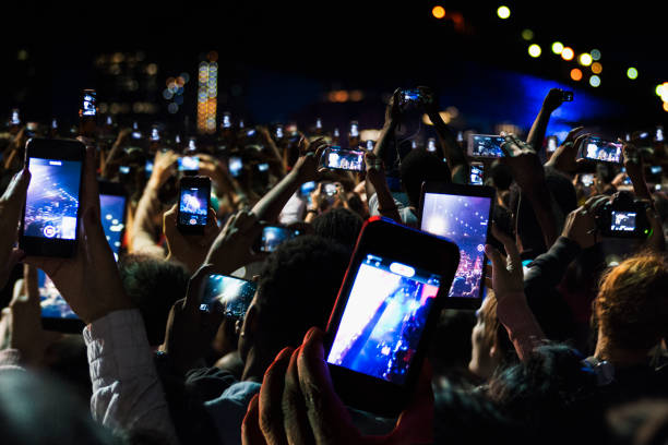 crowd of people recording video with cell phones at night - concert stock pictures, royalty-free photos & images