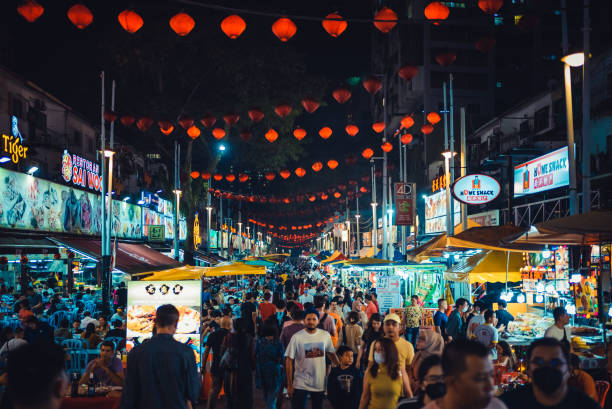 crowd of people walking in jalan alor food street is a popular tourist attraction in kuala lumpur city center - food stock pictures, royalty-free photos & images