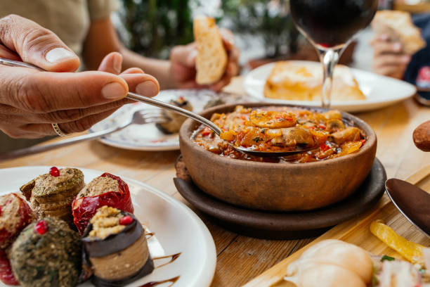 cuisine géorgienne traditionnelle. homme mangeant chashushuli végétarien aux champignons, avec phali - collation à base de noix, de divers légumes ou herbes et d’épices et de rouleaux d’aubergines, lobio dans un pot en argile