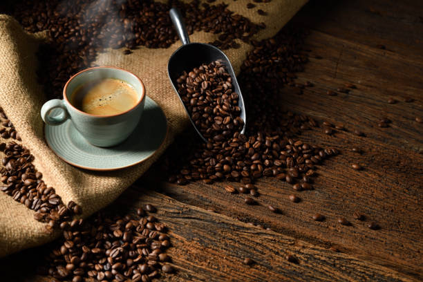 cup of coffee with smoke and coffee beans on old wooden background - coffee stock pictures, royalty-free photos & images