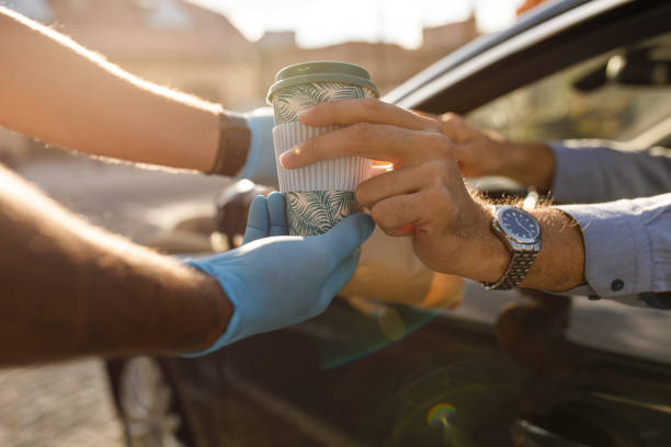 customer taking his coffee and food order from the service person at the drive through - junk food stock pictures, royalty-free photos & images