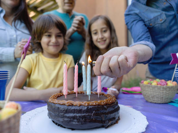 daddy lightining birthday candles while everyone waits to sing happy birthday to little boy - garden decoration stock pictures, royalty-free photos & images