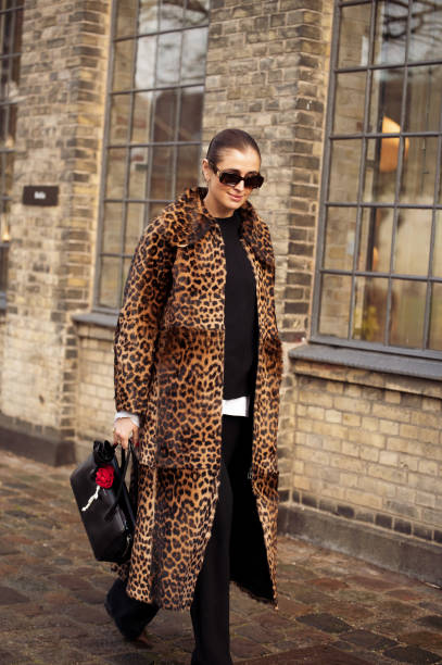 Darja Barannik wears black top, black pants, animal print coat, black bag with accessories outside the Munthe fashion show during the Copenhagen...