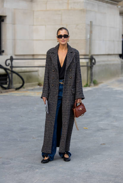 Darja Barannik wears grey coat, brown bag, denim jeans, black shirt outside Chanel during Womenswear Spring/Summer 2025 as part of Paris Fashion Week...