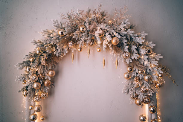 decorated christmas arch with snow-covered fir branches and gold toys: balls and icicles in sparkles. white, silver, grey and golden colors. concept of new year and christmas coming. new year's decorations for photo shoots an