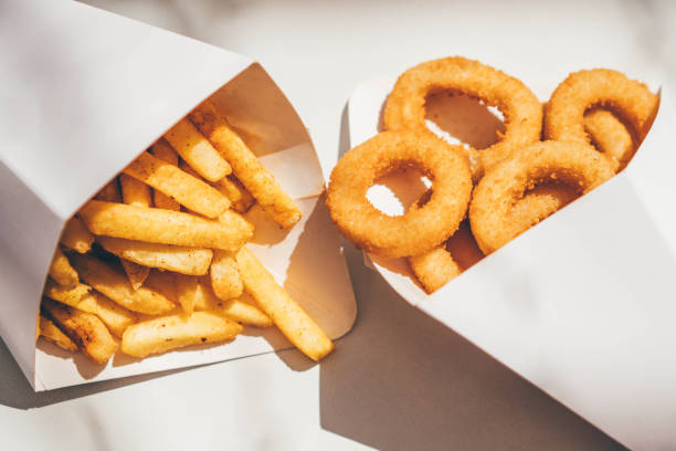 deep-fried onion rings and french fries. - junk food stock pictures, royalty-free photos & images