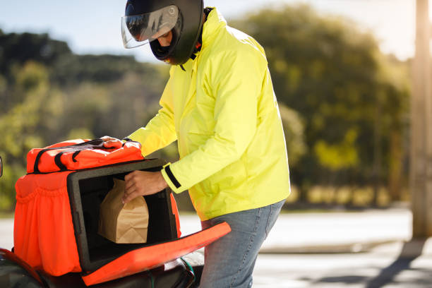 delivery man taking the order out of the backpack - motoboy - food stock pictures, royalty-free photos & images