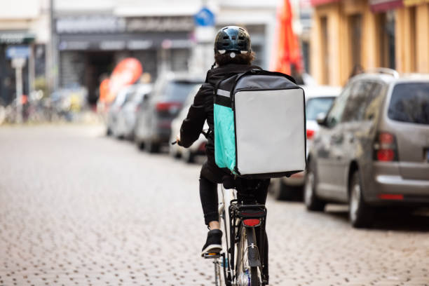 delivery person with thermal box on a bicycle in town - junk food stock pictures, royalty-free photos & images