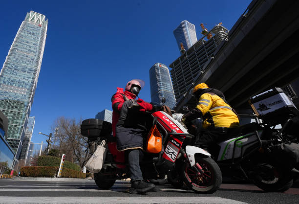 Delivery riders ride electric bikes on the road on February 20, 2025 in Beijing, China. JD.com, one of China's largest e-commerce platforms, and...