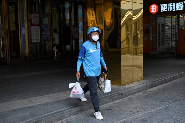 Delivery worker carries a take-away food order outside a mall in Beijing on June 20, 2022.