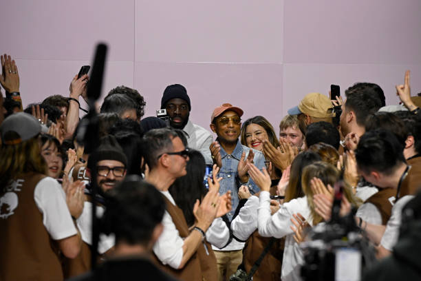 Designer Pharrell Williams celebrates with his design team on the runway during the Louis Vuitton Menswear Fall-Winter 2025/2026 show as part of...
