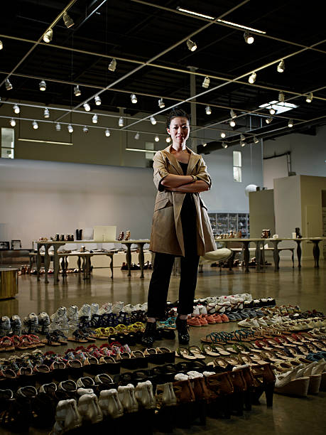 designer standing in showroom surrounded by shoes - fashion stock pictures, royalty-free photos & images