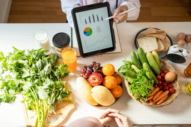 detox concept. afro woman patient of nutritionist drinking lemon water while doctor taking notes, close up - food stock pictures, royalty-free photos & images
