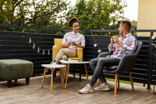 deux amis assis sur le balcon, discutant autour d’une tasse de café - garden decoration photos et images de collection