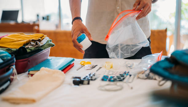 die hand eines mannes verpackt kosmetika und medikamente für die reise in eine tasche mit reißverschluss. - travel stock-fotos und bilder