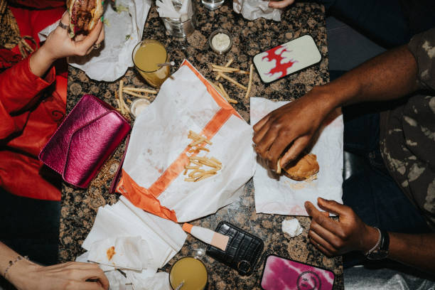 directly above shot of friends eating fast food and drinks on table at nightclub - junk food stock pictures, royalty-free photos & images
