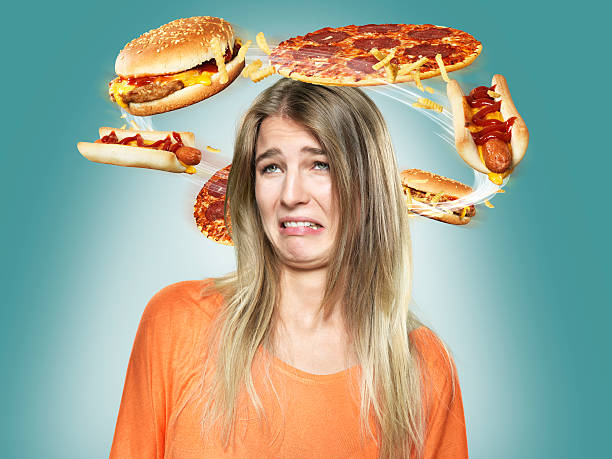 disgusted young woman with flying fast food around her head, composite - junk food stock pictures, royalty-free photos & images