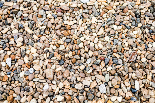 diverse collection of small pebbles and stones in various colors scattered on a surface in natural light - garden decoration stock pictures, royalty-free photos & images