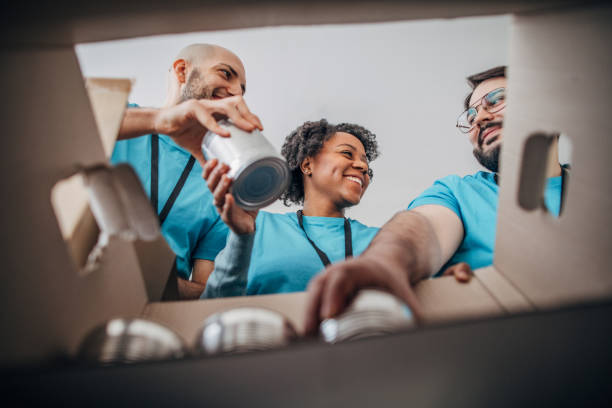 diverse volunteers packing donation boxes with canned food in food bank - food stock pictures, royalty-free photos & images