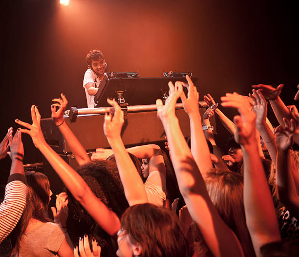 dj spinning at nightclub surrounded by crowd - concert stock pictures, royalty-free photos & images