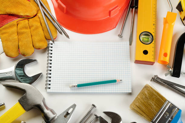 drawings and construction tools for professional construction or home repair on a white table. a notebook at the workplace of a foreman or carpenter. the concept of the construction industry, business. copy space. - home deco