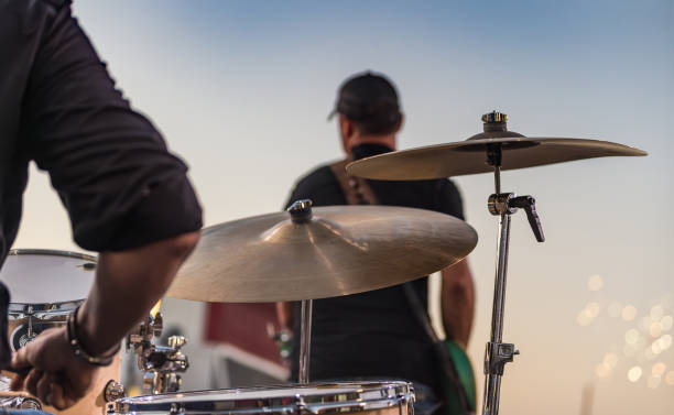 drummer sitting at a drum set and lead guitarist on stage as fireworks are shot off at the start of a live independence day concert - concert stock pictures, royalty-free photos & images