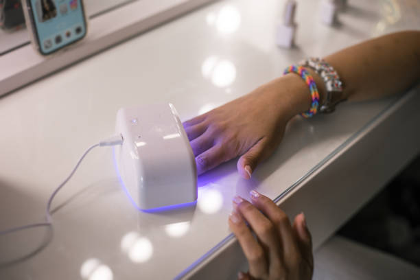 drying nails under uv lamp during manicure. - nails art stock pictures, royalty-free photos & images