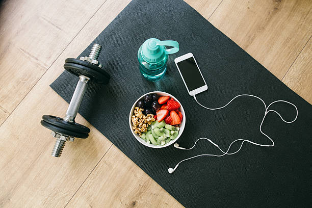 dumbbell, drinking bottle, fruit bowl and smartphone with earphones - food stock pictures, royalty-free photos & images