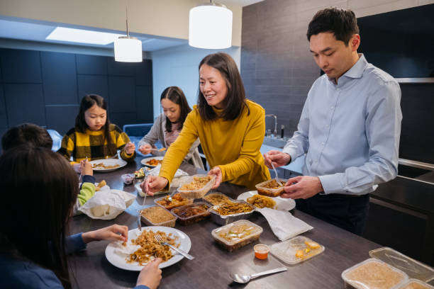 east asian family enjoying takeout food for dinner - junk food stock pictures, royalty-free photos & images