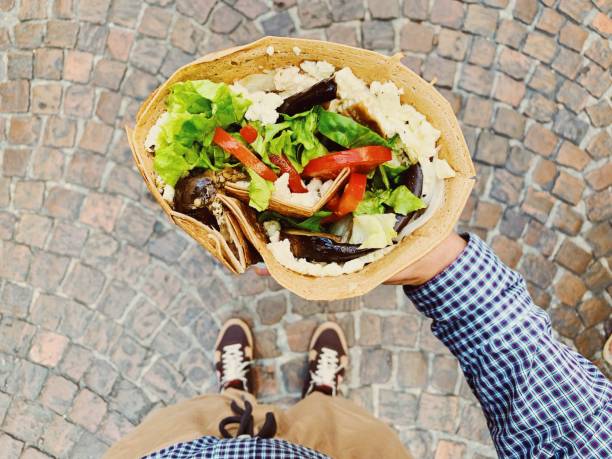 eating big french crepe pancake with vegetables, salad and cheese, personal persoective view - junk food stock pictures, royalty-free photos & images